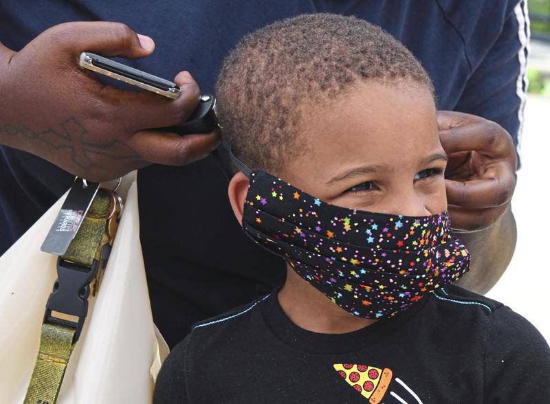Taneisha Freeman helps her son Davion Maynor, 5, to make adjustments to his new face mask Friday, June 26, 2020, in Pittsburgh's Arlington Heights neighborhood, for the Minority Emergency Preparedness Task Force (MEPTF) distribution of kits with masks, hand sanitizer, information about the coronavirus and prevention. (Darrell Sapp//Pittsburgh Post-Gazette via AP)