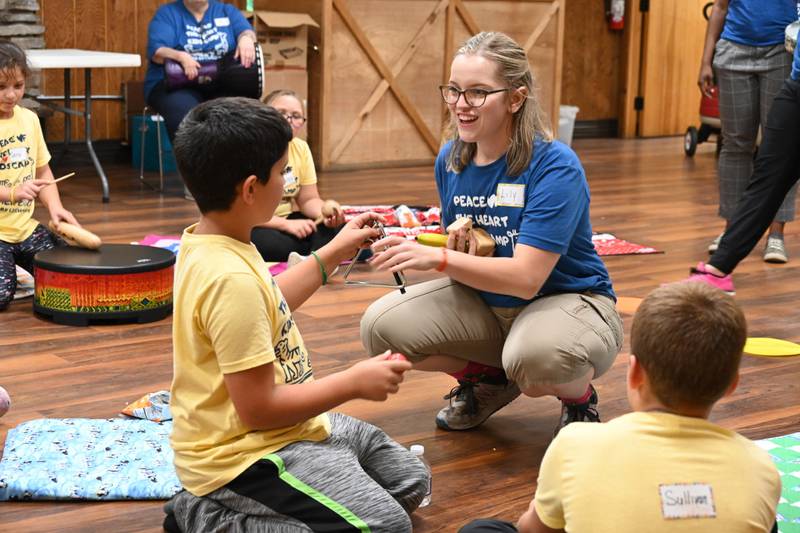 Music therapist Lily Fisher works with a camper to play the triangle at Pilcher Park Nature Center in Joliet during Lightways Hospice and Serious Illness Care’s “Peace of the Heart Children’s Grief Camp."