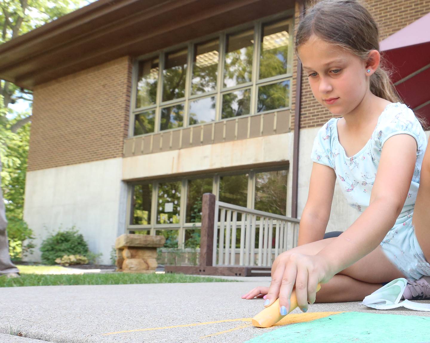 Charlie Caputo of Oglesby, colors the sidewalk in front of the Peru Public Library during their "Chalk the Walk" event on Tuesday, Aug. 13, 2024.