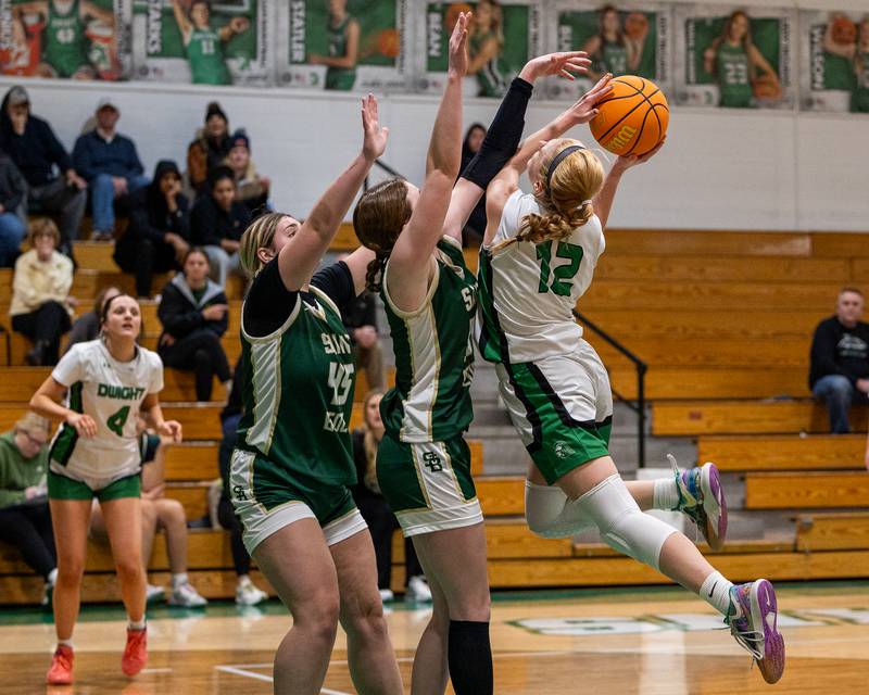 Dwight's Mikayla Chambers (12) leaps and lays ball up-into St. Bede's Lili McClain (23) and teammate Savannah Bray (45) on Monday, January 19, 2026 at the Krese Memorial Gymnasium in Dwight.