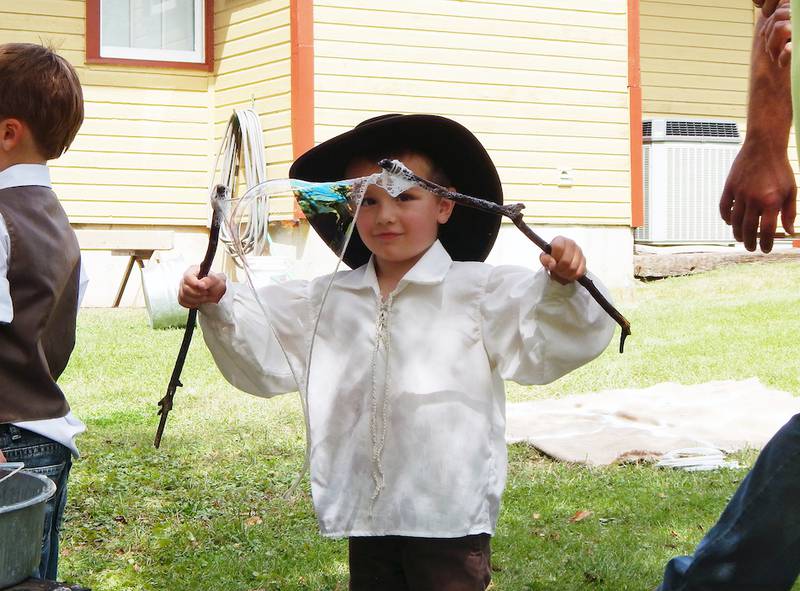 Eli Wellman, 2, of Genoa uses strings strung between two sticks and dipped in a soapy solution to make bubbles Sunday at the Kishwaukee Valley Heritage Society's annual Pioneer Day festival.