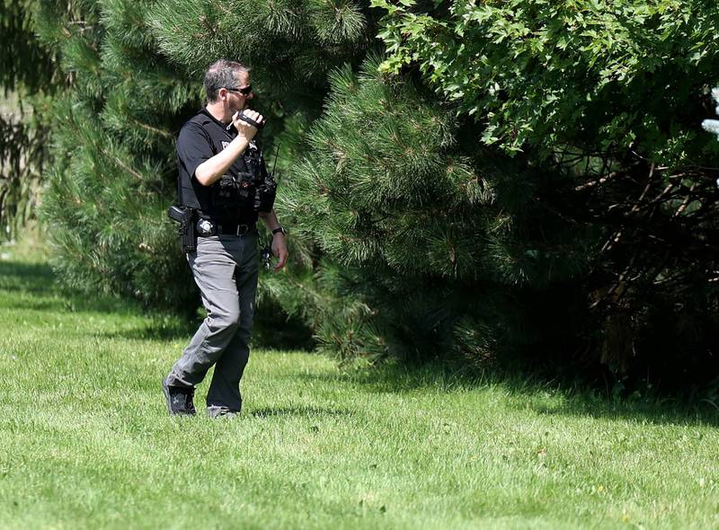 A DeKalb police officer takes video Monday, July 28, 2025, along the tree line that obscures a pond along the property on Ridge Drive between Sunflower Drive and Pickwick Lane as the investigation continues after a victim of an apparent drowning was recovered Sunday night.