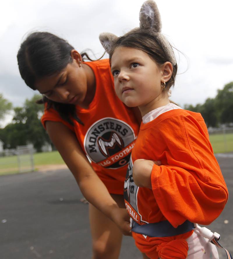 Tessa Jesky, 6, looks out at the playing field as Jessica Alva puts flags on her for the Chicago Bears Mini Monsters Flag Football Camp on Wednesday, July 16, 2025. at McCracken Field in McHenry.