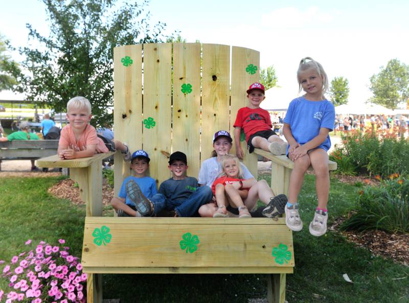 What do you do at the end of fair week?  Sit for a spell. That's what these kids from Somonauk and Lee did in the big chair at the Lee County Fairgrounds on Sunday, July 30, 2023. Pictured, left to right, are: Henry Gudmunson, 4; Harlan Gudmunson, 7=6; Knute Gudmunson, 8; Chelsea Huss, 11; Thea Huss, 4; Micah Huss, 7; and Westlyn Huss, 6.