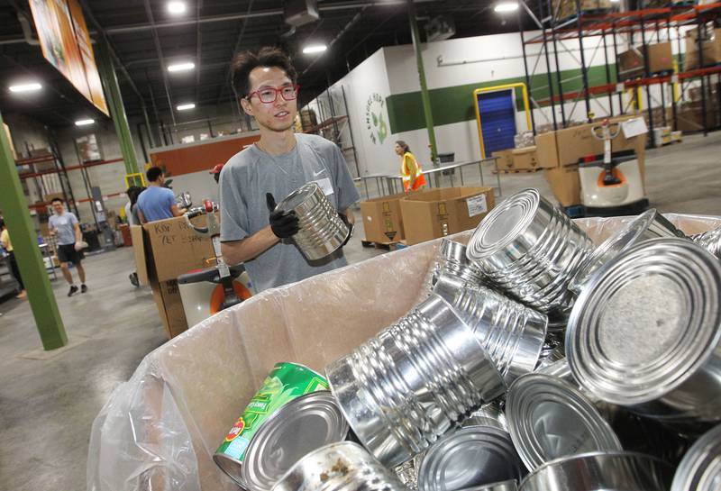 Caspar Hu, of Glenview puts dented large cans of vegetables into a separate box at the Northern Illinois Food Bank on August 19th in Lake Forest. The North Suburban Center recently celebrated it’s one-year anniversary at this location.  
Photo by Candace H. Johnson for Shaw Local News Network
