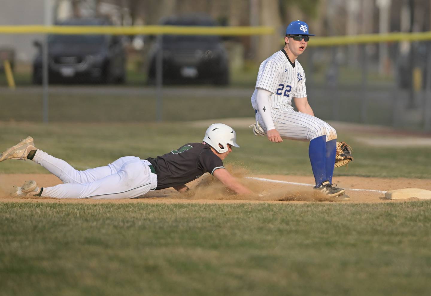 Glenbard West’s Jack Walti dives safely back to first as Geneva’s Gavin Dworak waits for the pickoff throw in a baseball game in Geneva on Wednesday, Mar. 25, 2026.