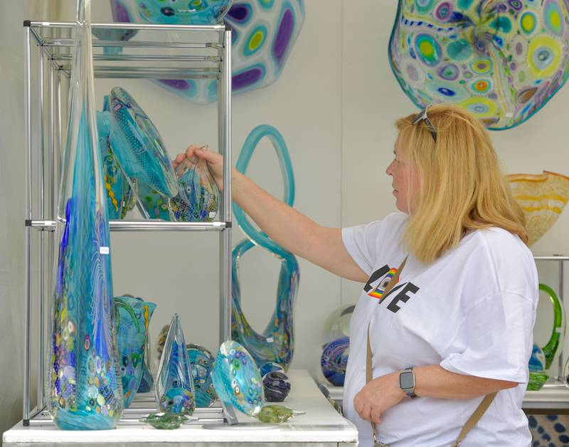 Lori Jackson of Naperville looks at some glass works from Garrelts Glass during the St. Charles Fine Art Show on Saturday, May 27, 2023.