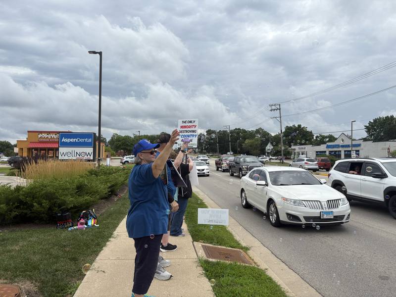 Protesters wave at passersby during a protest in McHenry July 26, 2025.