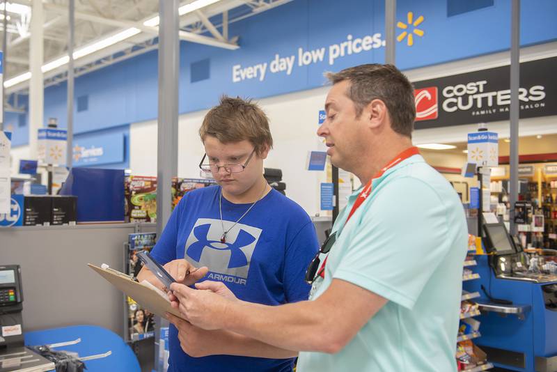 Gage Hoefte and teacher Richard Melcher add up items while checking out at the the Sterling Walmart. The group was spot on with their estimations before scanning the products.