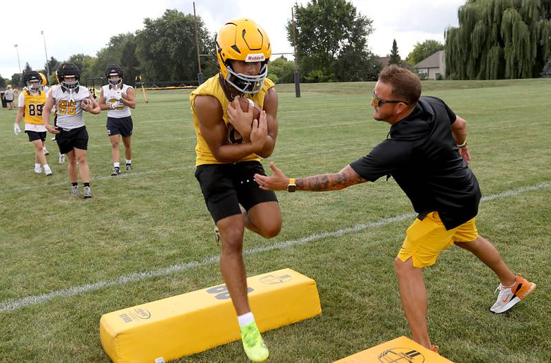 Jacobs Head Coach Brian Zimmerman(right) tries to knock the football away from Justin Gonzalez during football practice on Tuesday, August 15, 2025, at Jacobs High School in Algonquin.