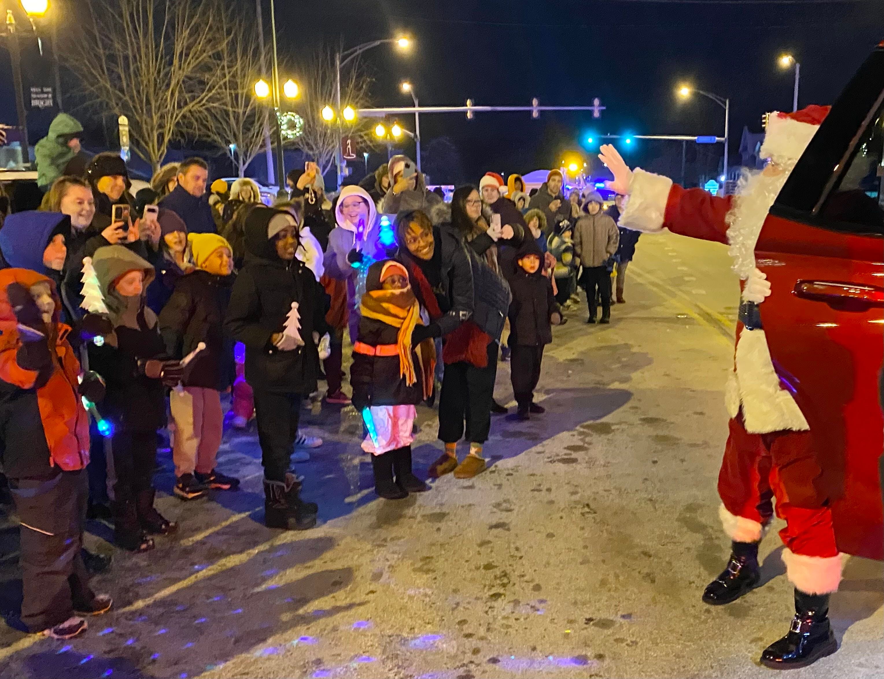 Santa Claus waves as he greets waiting on Friday, Dec. 5, 2025, ready to walk with him downtown at the Sycamore Chamber of Commerce's annual Walk with Santa.