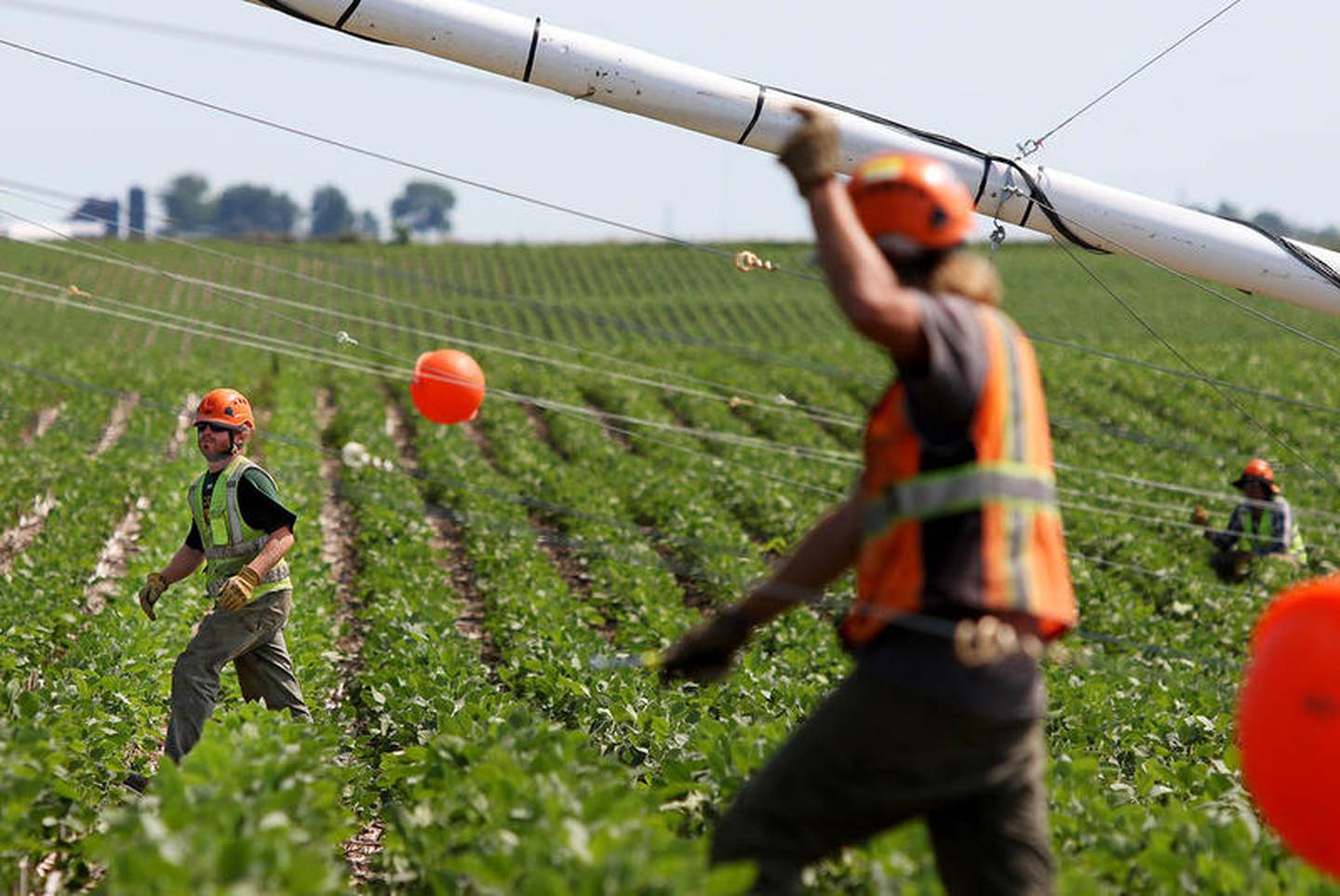 Contractors (from left:) Remmington Fox, Michael Williams, and Michael Sibalski work on erecting a wind testing tower on Monday, July 17, 2017 in a soy bean field on MacQueen Road in South Grove.  The tower, also known as a MET (meteorological evaluation tower), is one of two highly contested structures at recent county and zoning meetings.