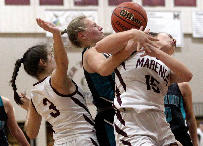 Marengo’s Emilie Polizzi, right, and Keatyn Velasquez, left, battle Woodstock North’s Caylin Stevens, center, in varsity girls basketball at Marengo Tuesday evening.