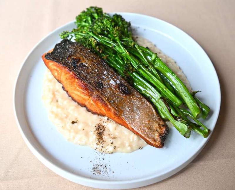 Wood-fired Atlantic salmon is served on risotto with roasted broccolini.