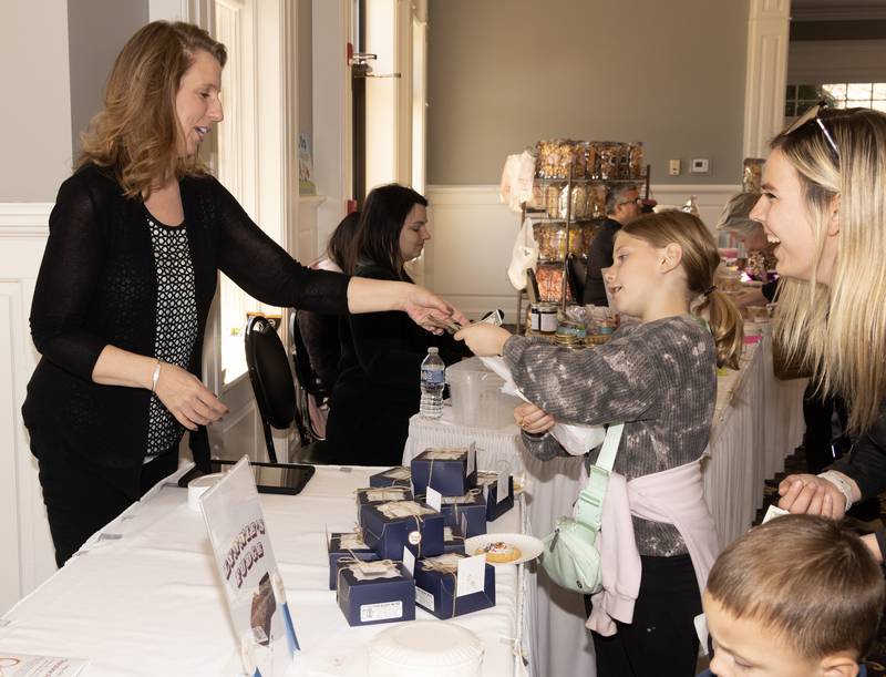 Lynnie Logan of Gourmet Artisan Desserts + by Lynnie's accepts payment from Cierra Godwin, 9, of Ottawa for a box of fudge.
