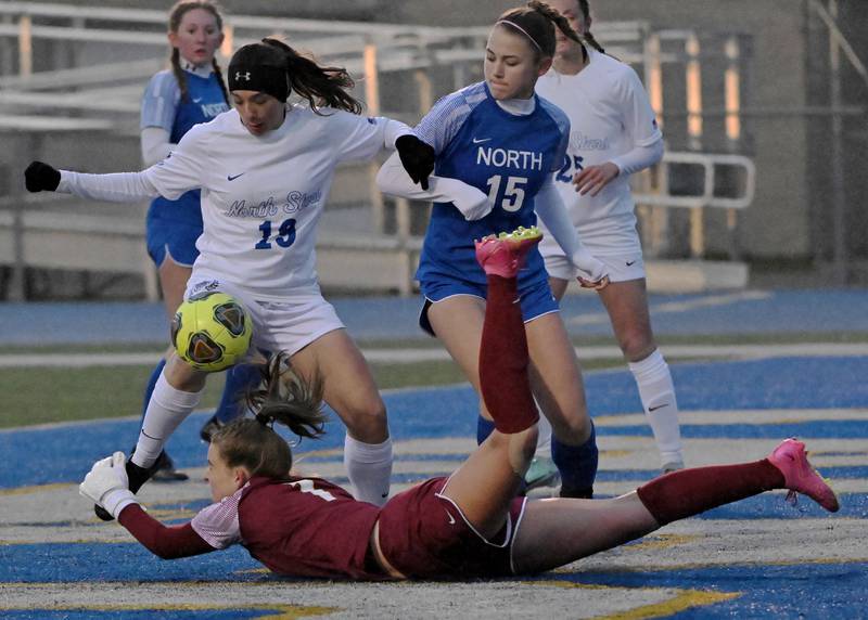 Wheaton Northgoalkeeper Zoey Bohmer dives to stop the shot by St. Charles North’s Laney Stark in a girls soccer game in Wheaton in April 2024.