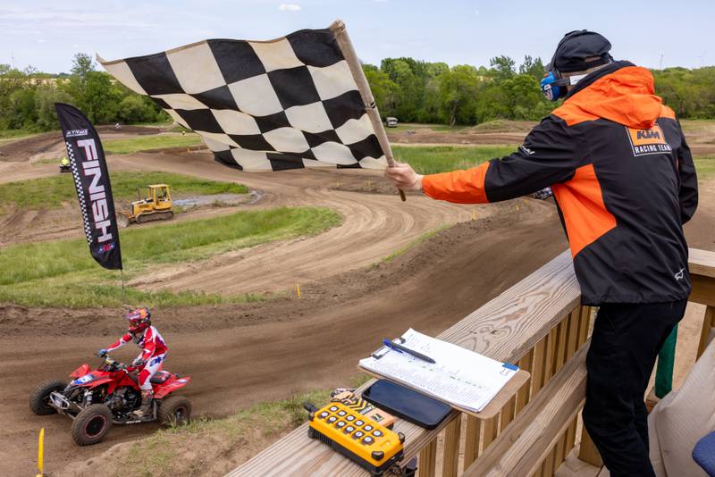 Garrett Pistole waves the checkered flag as WMX women's pro rider Emma Wray crosses the finish line and securing her win at the ATVMX Championship race on May 24, 2025 at Sunset Ridge MX in Walnut.