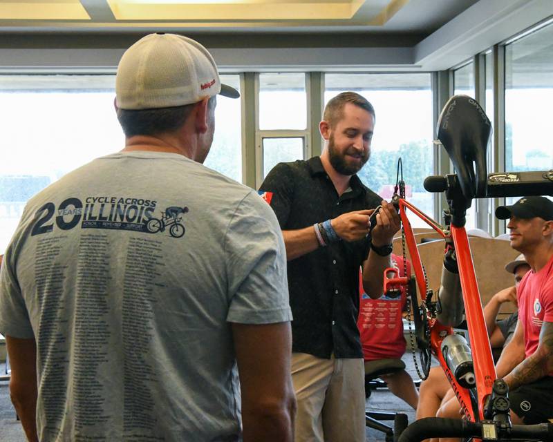 David Parks, right, from The Cyclery and Fitness Center in Edwardsville, IL works on Aaron Woodruff’s bike an Illinois State University police officer on Saturday July 12, 2025, as Cycle Across Illinois stops at Northern Illinois university in DeKalb for the night.