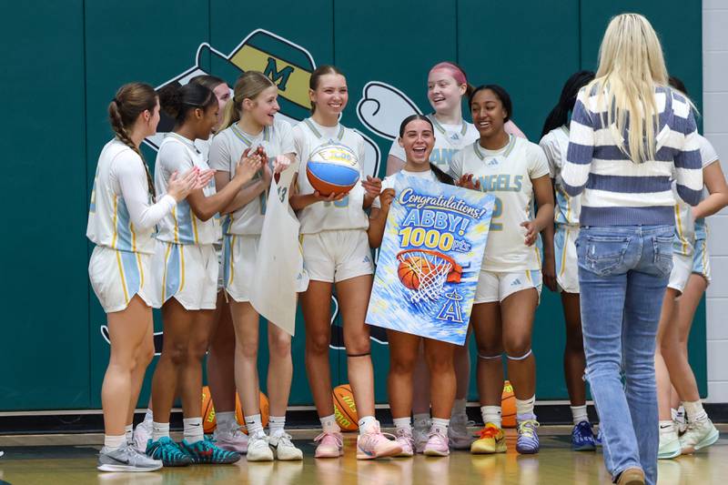 Joliet Catholic's Abby Dulinsky, at center with ball, smiles as her teammates celebrate her 1,000th point following their 72-28 victory over Beecher in the IHSA Class 2A Bishop McNamara Regional semifinals on Monday, Feb. 16, 2026.