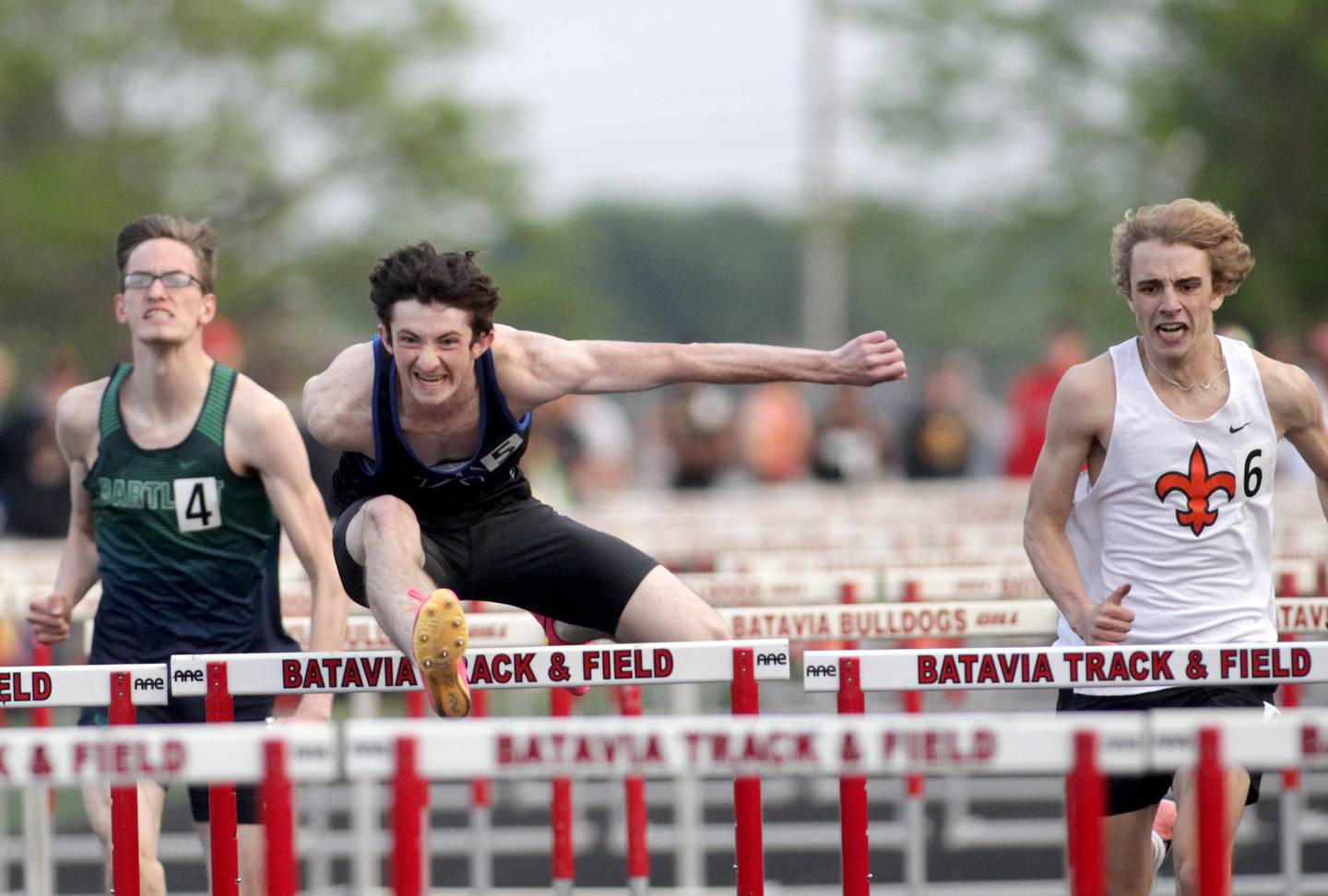 St. Charles North’s Bryce Thomas (center) flies over the hurdle in the 110-meter hurdles during the Class 3A Batavia track and field sectional on Thursday, May 18, 2023.