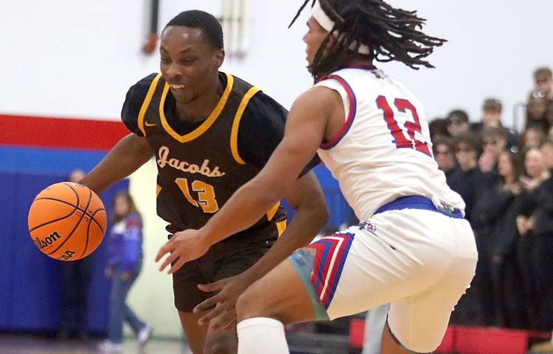 Jacobs’ Elijah Bell, left, moves the ball as Dundee-Crown’s  Anthony Spain defends in varsity boys basketball on Friday, Dec. 12, 2025, at Dundee-Crown High School in Carpentersville.