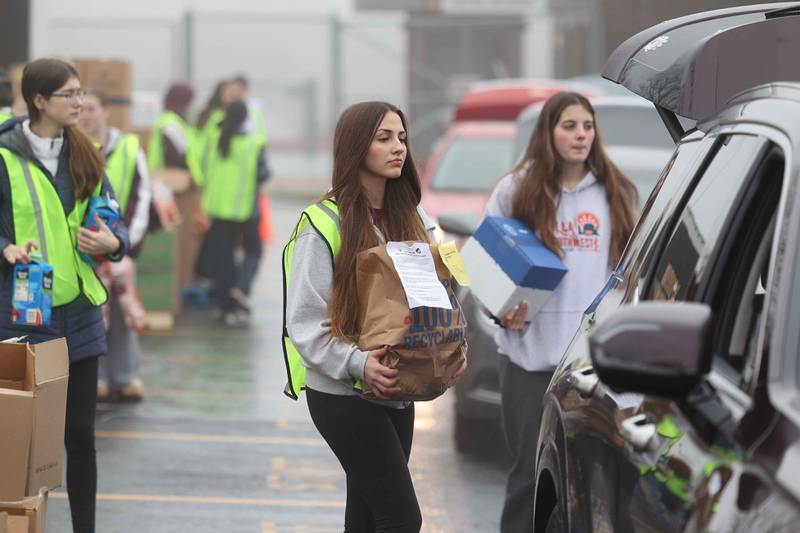 Lockport High School freshman Maggie Fontaine loads donated food into a trunk of a vehicle during ShareFest at Lockport Township High School East campus on Sunday, Dec. 15, 2024.