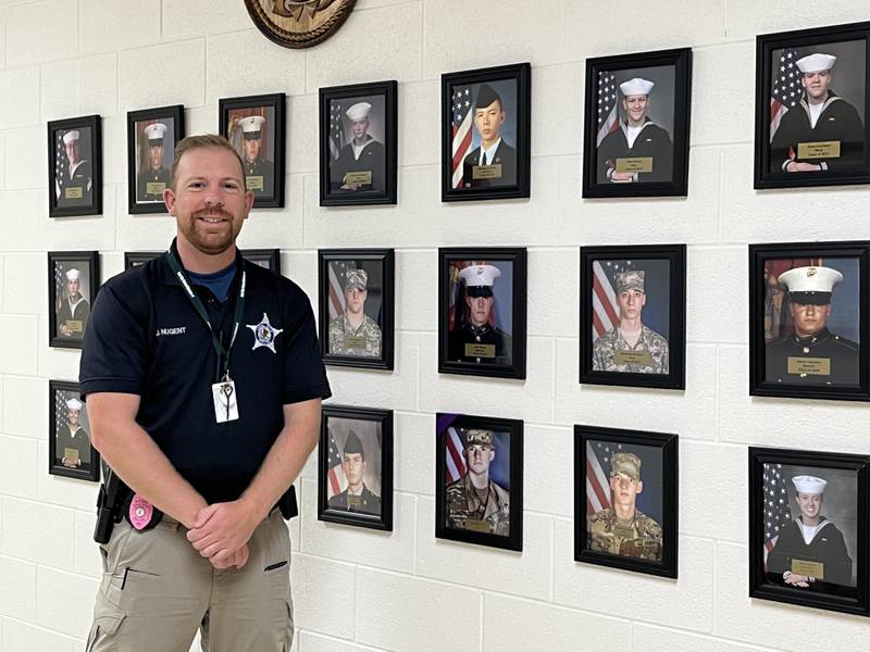 Officer Josh Nugent in the Coaler Hero Hallway, a section of the school's administrative wing dedicated to photos of Coaler alumni who served in the military.