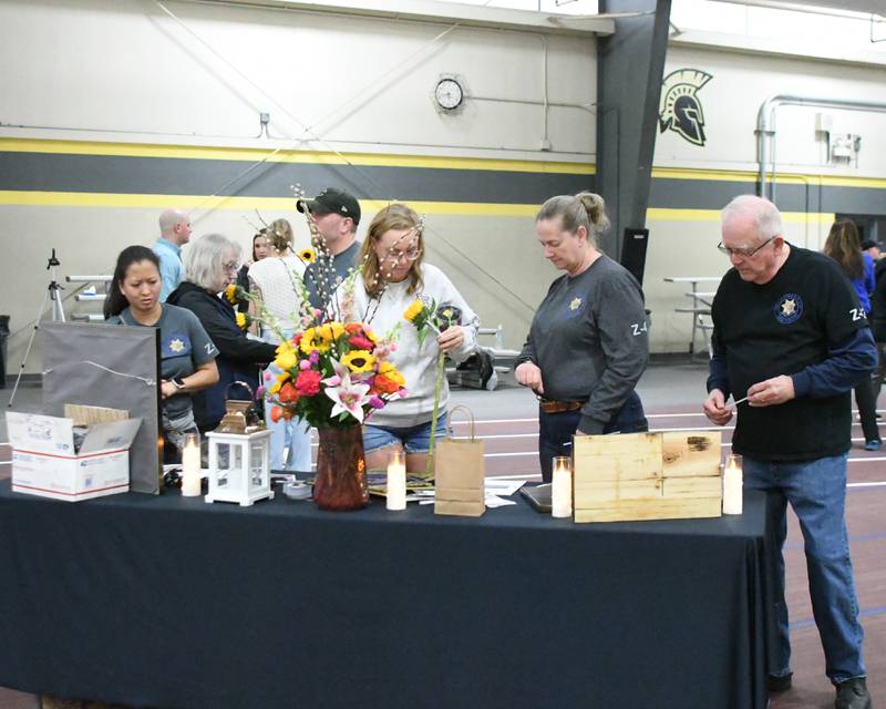 Community members view a display table at a memorial vigil on Saturday, March 29, 2025, to mark one year since the late DeKalb County sheriff's deputy Christina Musil, 35, was killed in the line of duty in a rear-end car crash in Waterman while on patrol on March 28, 2024. The vigil was held at Sycamore High School's field house.