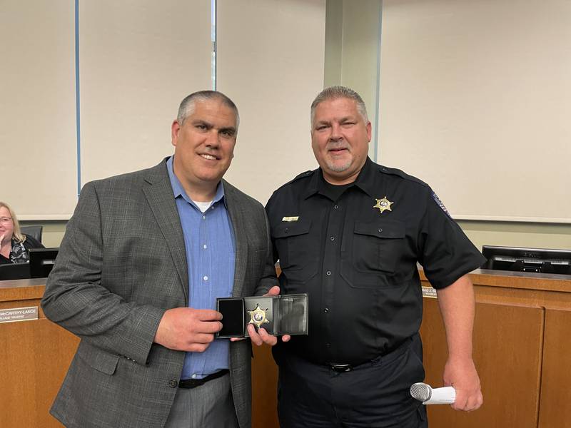 Oswego Police Chief Jeff Burgner, right, presents Oswego retiring deputy chief Kevin Norwood with a retirement badge at the May 16 Oswego Village Board meeting.