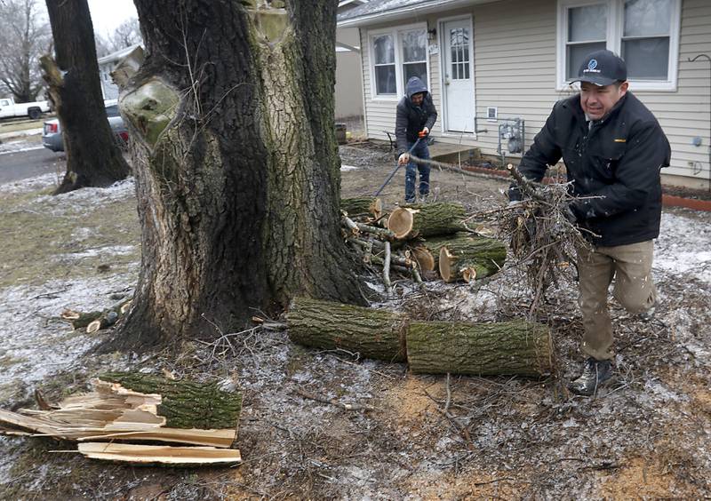 Rodolfo Lopez and his brother Arturo Lopez clean up Rodolfo Lopez’s yard Thursday, Feb. 23, 2023, in the 4900 block of State Street in Crystal Lake, after cutting up tree branches that came down in the ice storm. McHenry County residents recovered Thursday from a winter storm that knocked down trees and caused power outages throughout the county.