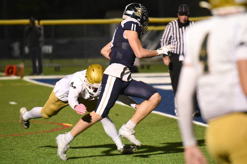IC Catholic's Grant Bowen (11) evades a tackle attempt from Bishop McNamara's Coen Demack on his way in for a touchdown during an IHSA Class 3A second round playoff game at IC Catholic Friday, Nov. 7, 2025.