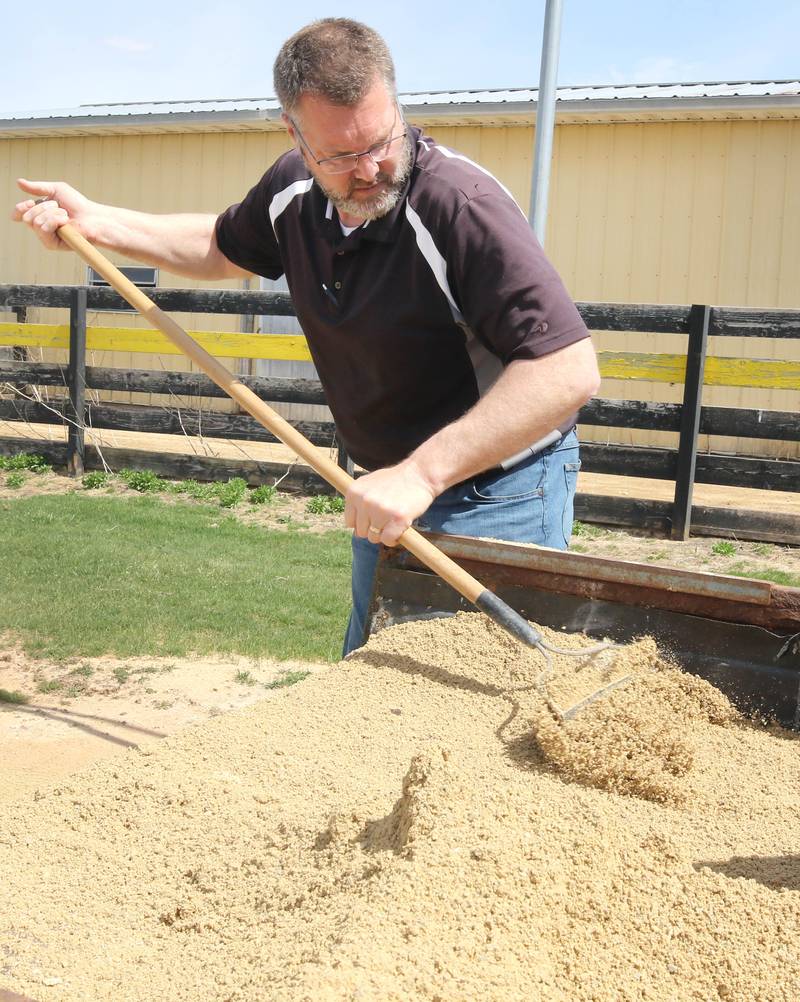Mark Ekstrom, director of buildings and grounds for Sycamore Community School District 427, rakes dirt into low spots Tuesday, April 11, 2023, in the batting cage behind the softball field at Sycamore High School.