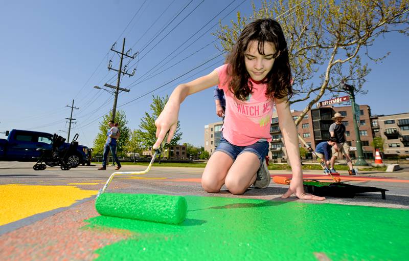 Lydia Lynn, 12 of St. Charles rolls out some green paint as she participates in the St. Charles Art CouncilÕs ÒPaint the RiversideÓ to change out the street mural in the intersection of Walnut and Riverside Avenues on Saturday, May 10, 2025 in St. Charles.