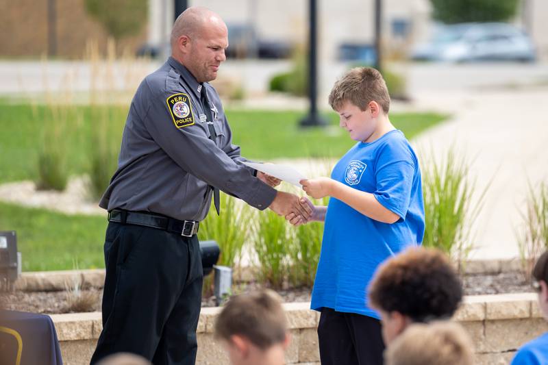 (left to right) Community Service Officer Blake Frund awards certificate to graduate at the first annual Juvenile Police Academy graduation ceremony on Friday, July 25, 2025 at the Peru Police Department in Peru.