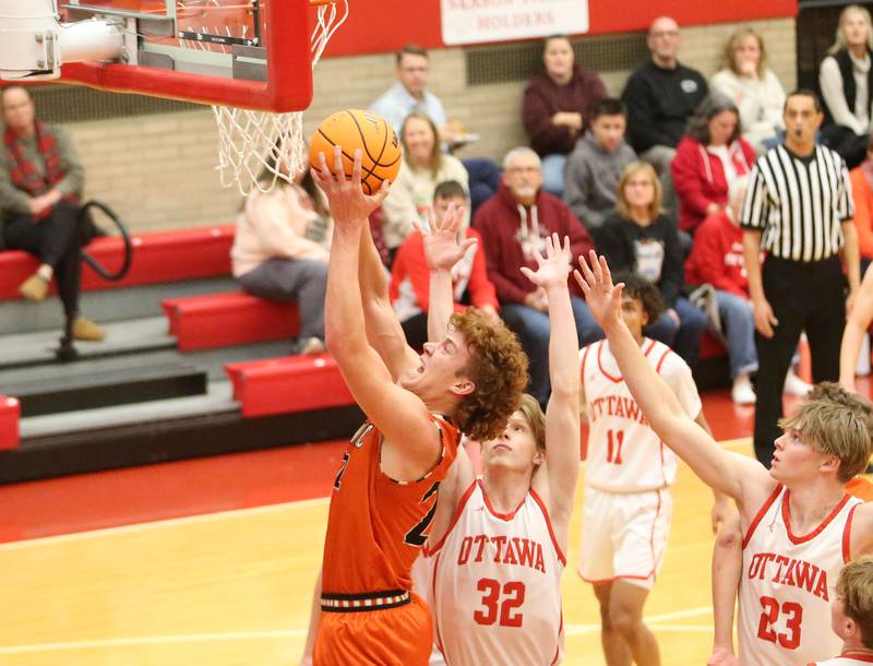 Sandwich's Dom Rome runs in the lane to score on a layup against Ottawa's Aric Threadgill and teammate Owen Sanders on Wednesday, Dec. 4, 2024 in Kingman Gym at Ottawa High School.