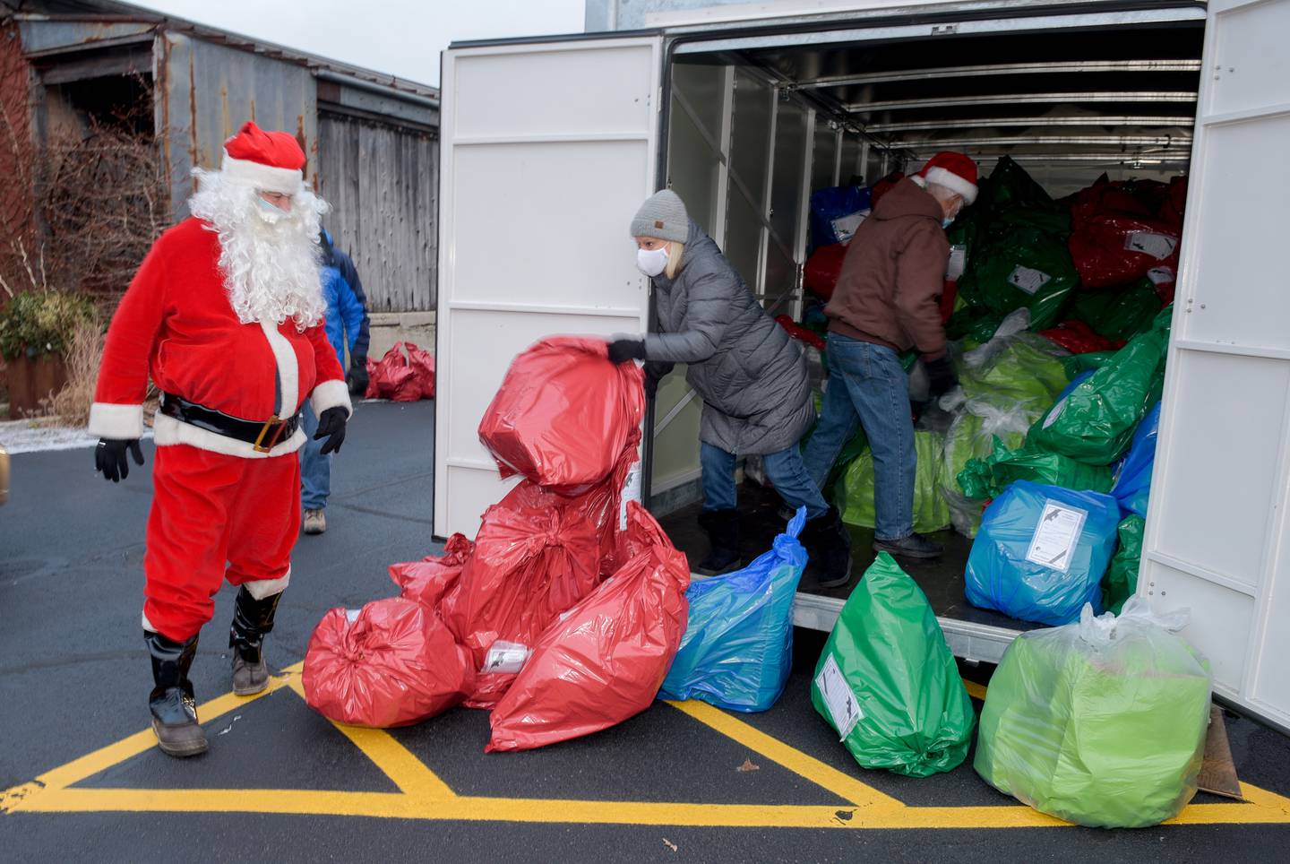 Goodfellows of Sycamore volunteers Santa, Brick Van Der Snick and Penny White unload a trailer full of Christmas gifts for the needy at Blumen Gardens in Sycamore on Thursday, Dec. 24, 2020.