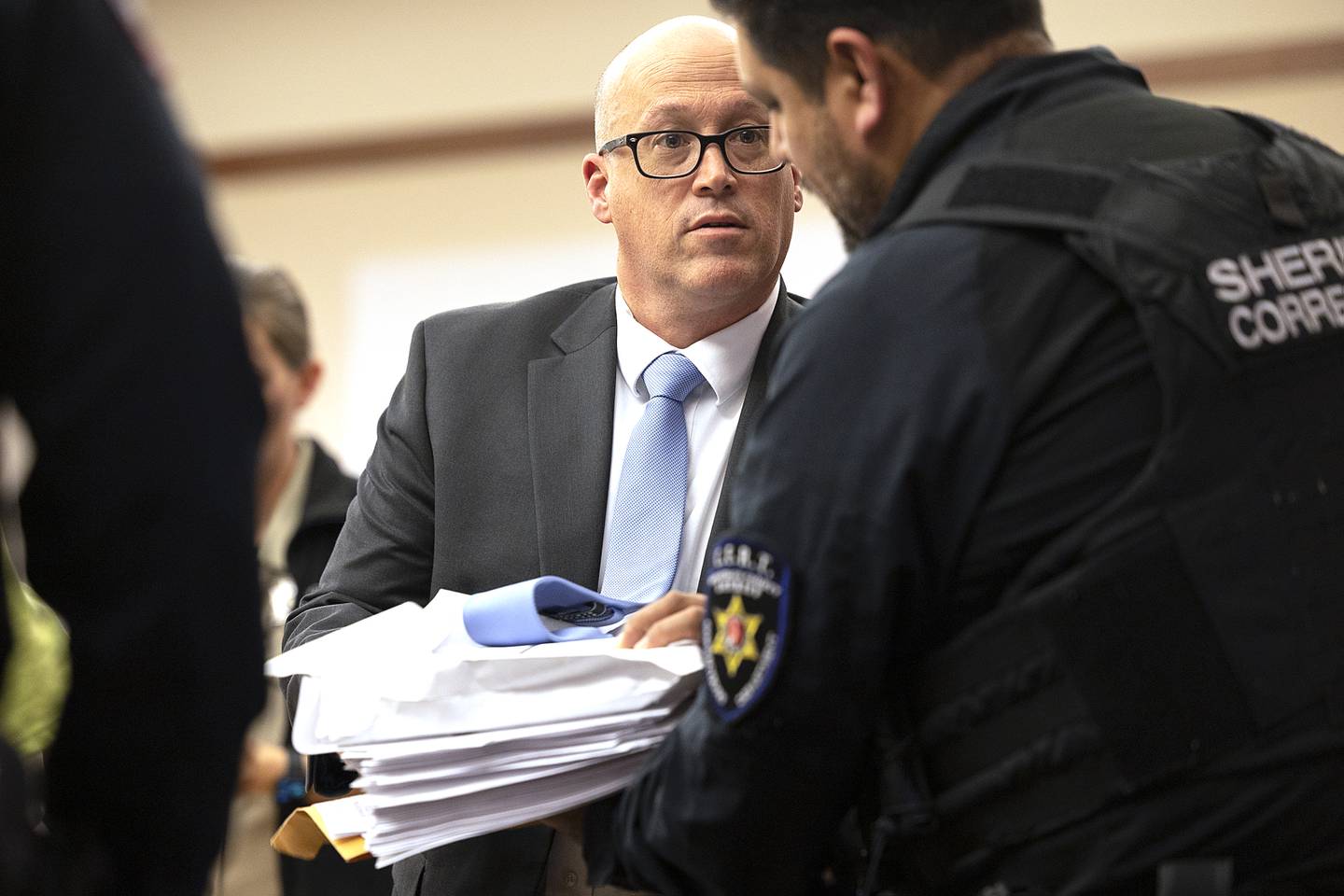 Ogle County public defender Michael O’Brien hands over paperwork to Jonathon Gounaris’ handlers Thursday, Nov. 21, 2024. Gounaris, 32, is being charged with four counts of attempted first-degree murder on top of several other charges.