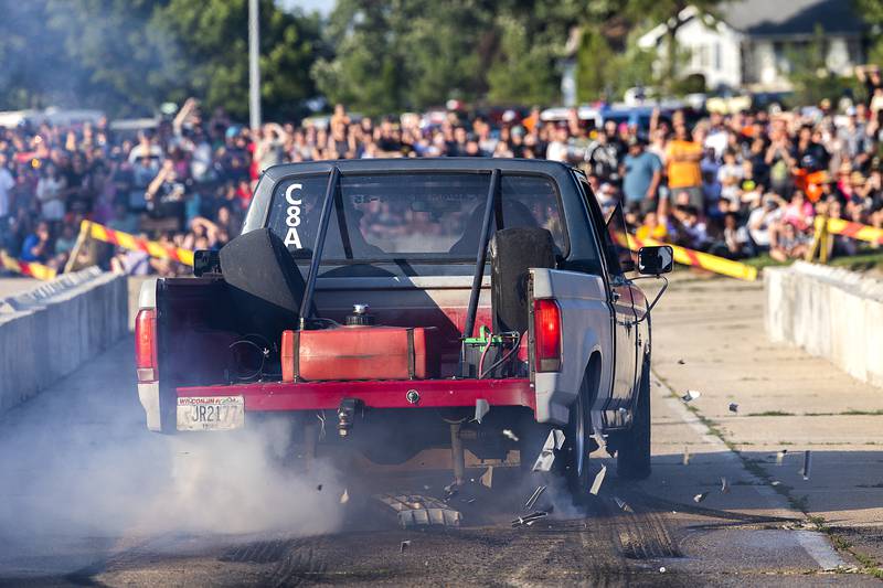 The grill is jostled off the front of a dragster's truck Thursday, June 19, 2025, as Sick the Mag drivers put up a burnout show in Rock Falls.