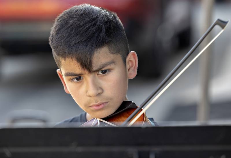 Santiago Rivera, 9, focuses on his music while giving a violin demonstration Wednesday, July 23, 2025, at Dixon City Market. Viva Performing Arts School set up a booth to showcase some of their students.