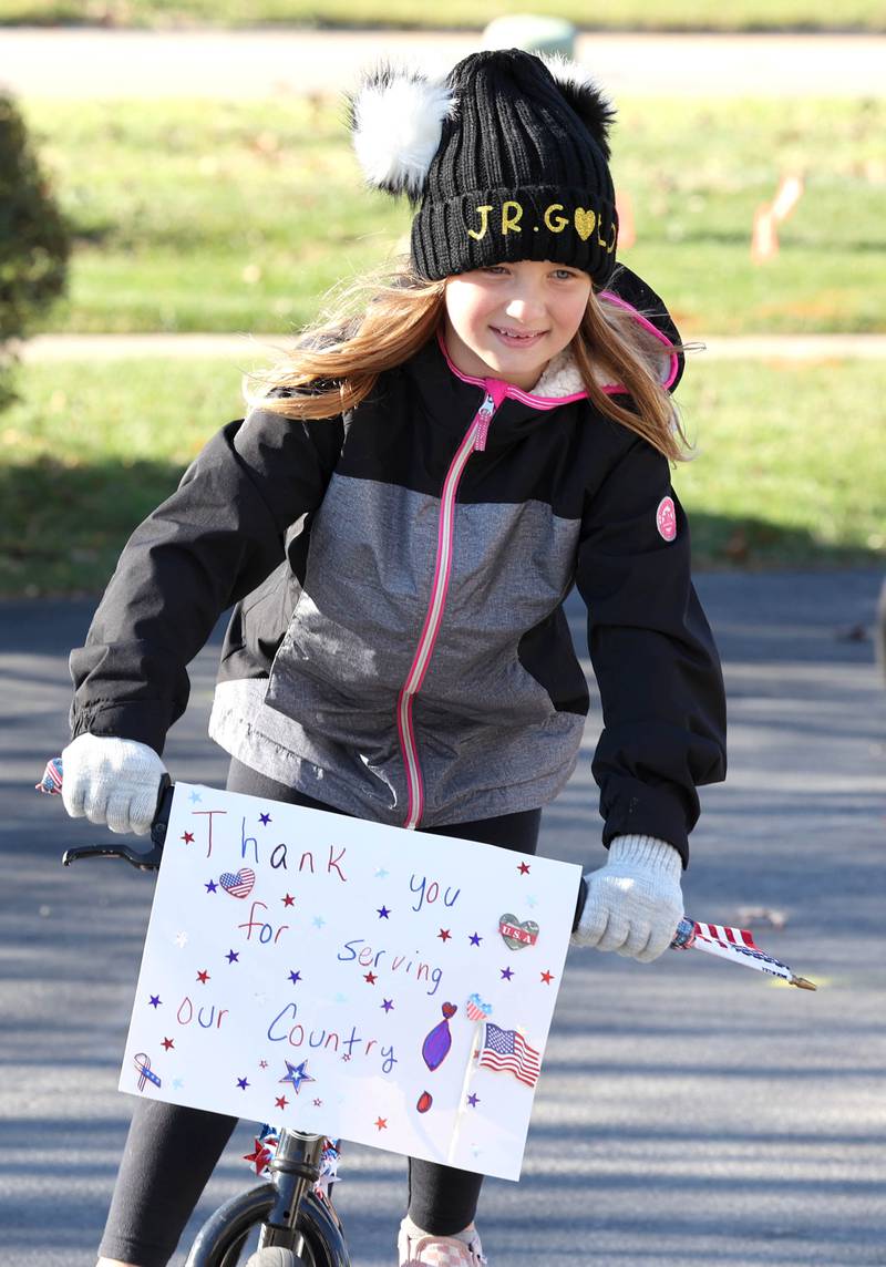 Johanna Kunkel, 7, from Sycamore, along with her siblings and grandma ride in a small parade on Veterans Day, Friday, Nov. 11, 2022, for the veterans at the Grand Victorian assisted living facility in Sycamore. Her grandma Joann Kunkel read a story in the Midweek that contained a quote from one of the veterans at the facility that lamented the lack of a parade. So she and her grandkids decided to have one for them.