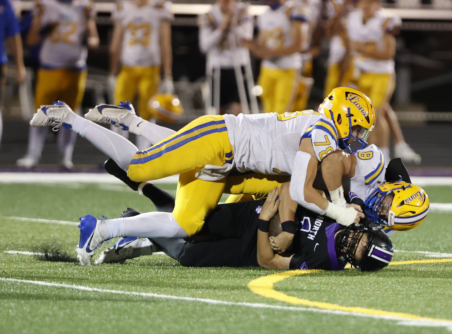 Downers Grove North's Owen Kansu (1) is smothered by the Lyons' Pat Cheney (8) and Ayman Soltan (78) during the varsity football game between Downers Grove North and Lyons Township on Friday, Oct. 11, 2024 in Downers Grove.