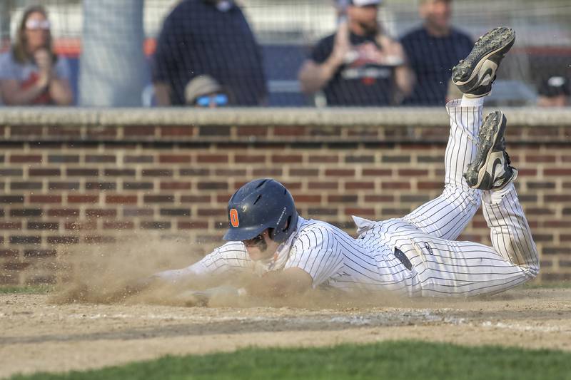Oswego's Quinn Stanley (12) slides into home during baseball game between Plainfield North at Oswego, Thursday, April 24, 2025 in Oswego.