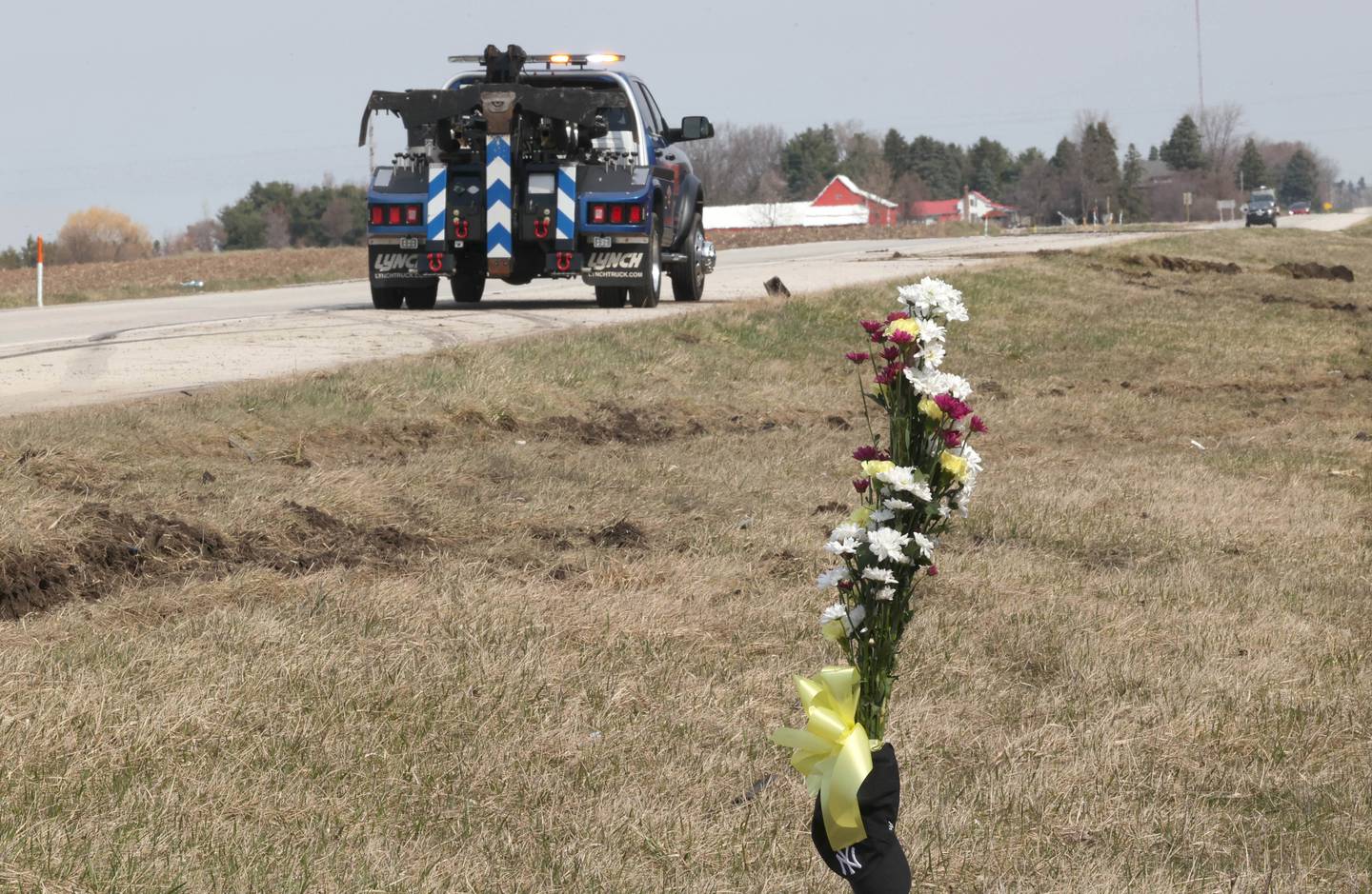 A tow truck sits near a memorial Friday, March 29, 2024, at the site on Route 23 three-quarters of a mile south Perry Road, where a DeKalb County Sheriff’s deputy was killed in a crash early Friday morning in DeKalb County. Ruts in the grass and skid marks were visible at the cash site.