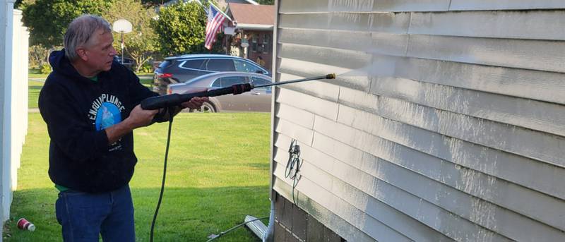 Brian Johnson uses a power washer on the siding of an Ottawa south side home, one of Saturday's Labor of Love projects.
