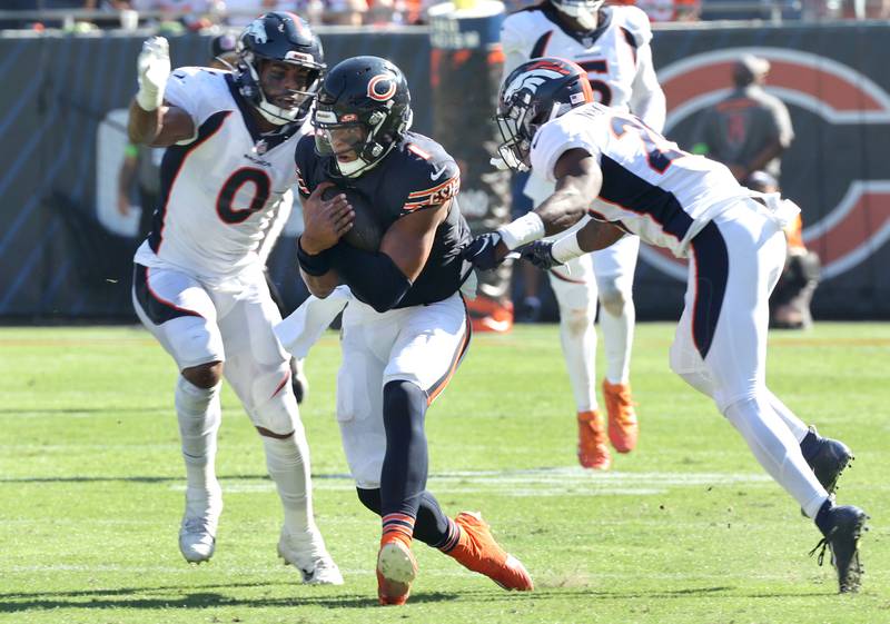 Chicago Bears quarterback Justin Fields scrambles for yardage running between two Denver Bronco defenders during their game Sunday, Oct. 1, 2023, at Soldier Field in Chicago.