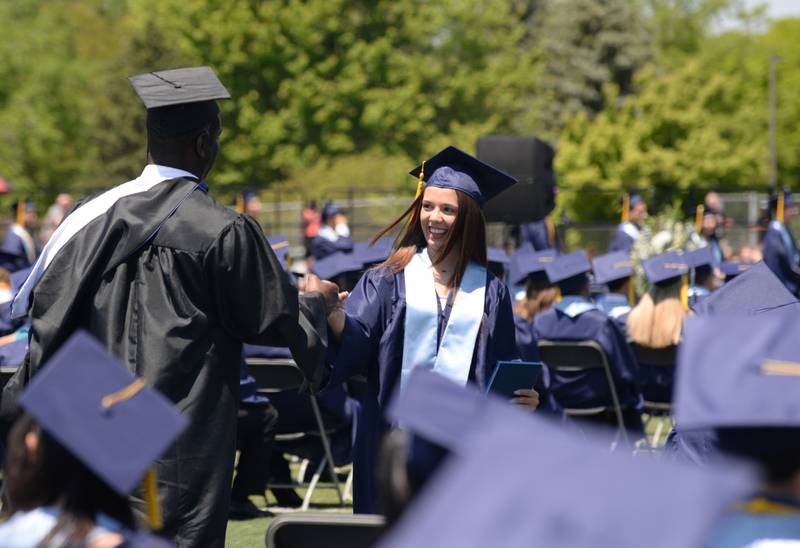 Downers Grove South graduates including Kaitlyn Montano receives a fist pump from teacher, Mr. Lowery during the graduation ceremony Sunday May 21, 2023.