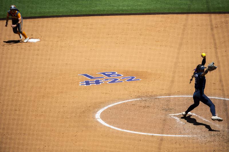 FILE  - "LB #22," in honor of James Madison softball catcher Lauren Bernett, is written on the infield behind Liberty pitcher Emily Kirby, right, during an NCAA college softball game against Tennessee at Liberty Softball Stadium in Lynchburg, Va., April 27, 2022. There has been a lot of talk about the mental health struggles that many young athletes face, the pressures and vulnerabilities that can seem overwhelming — especially to those who feel compelled to shield their pain from the outside world. (Kendall Warner/The News & Advance via AP, File)