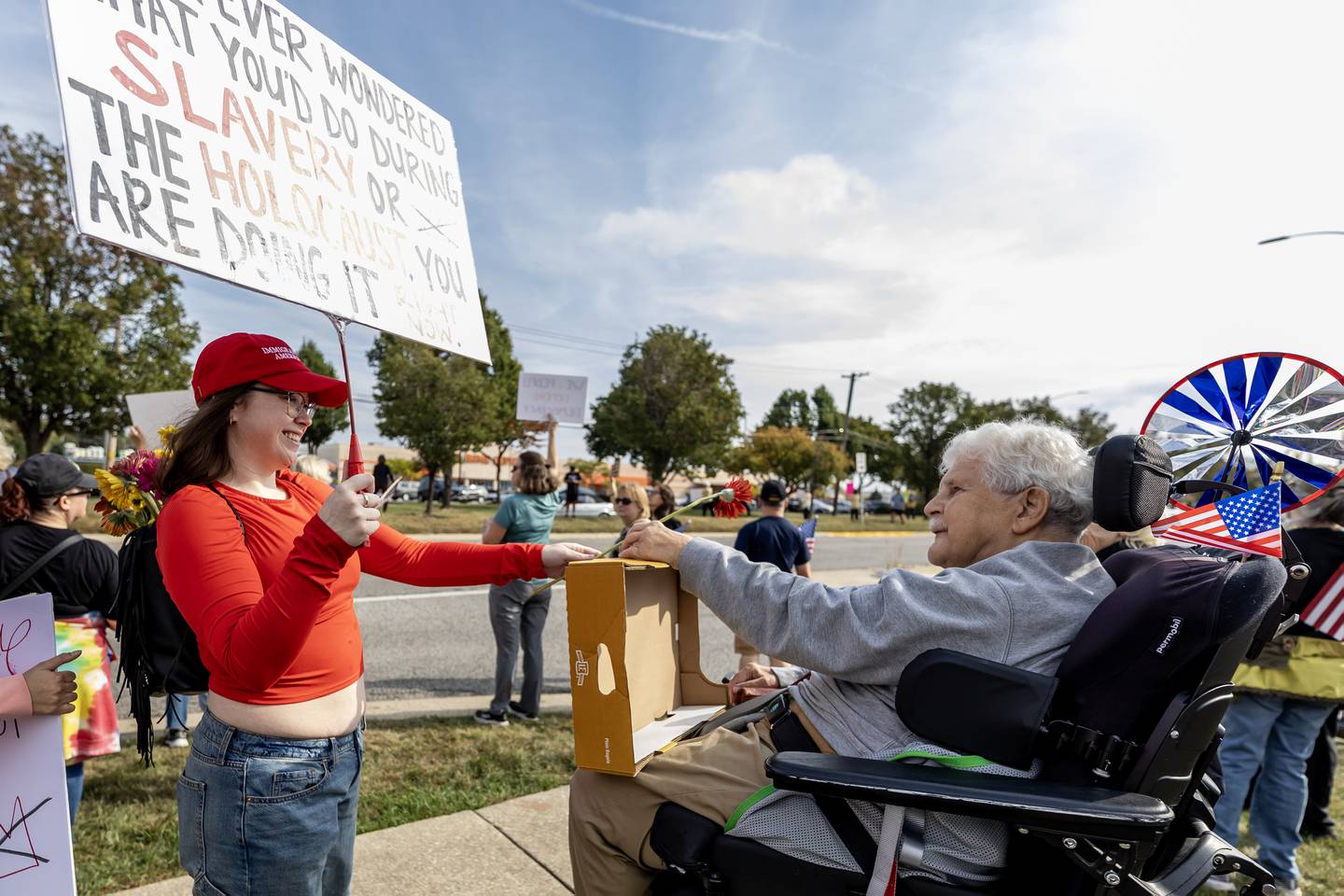 Emily Trudel hands Medard Narko a flower during the No Kings Protest at Mall Loop Drive in Joliet on Oct. 18, 2025.