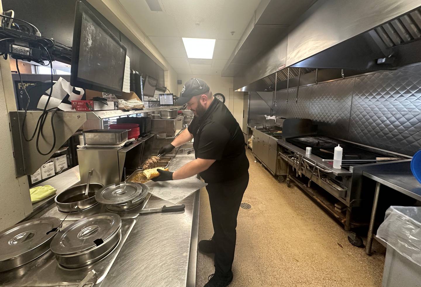 Frankie Radochonski, a multi-unit Pop’s Beef owner operating locations in Romeoville, Joliet, and Shorewood, places beef on a sandwich in a Pop's kitchen.
