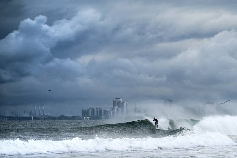 A surfer rides a wave as clouds gather above Bolsa Chica State Beach in Orange County, Calif., on Saturday, Nov. 15, 2025. (AP Photo/Noah Berger)